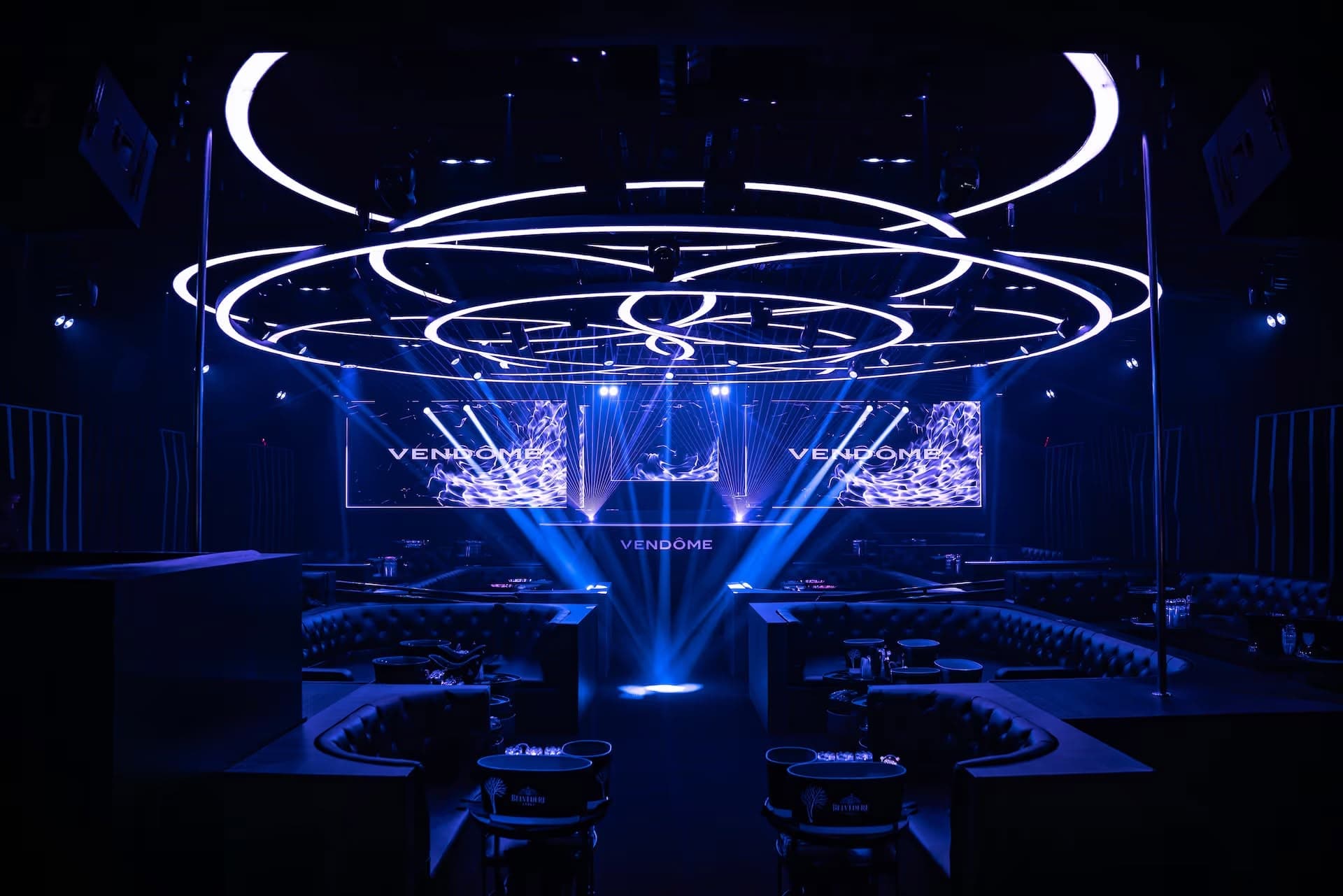 The room at Vendôme: a white ring chandelier over tufted booths, looking toward the stage