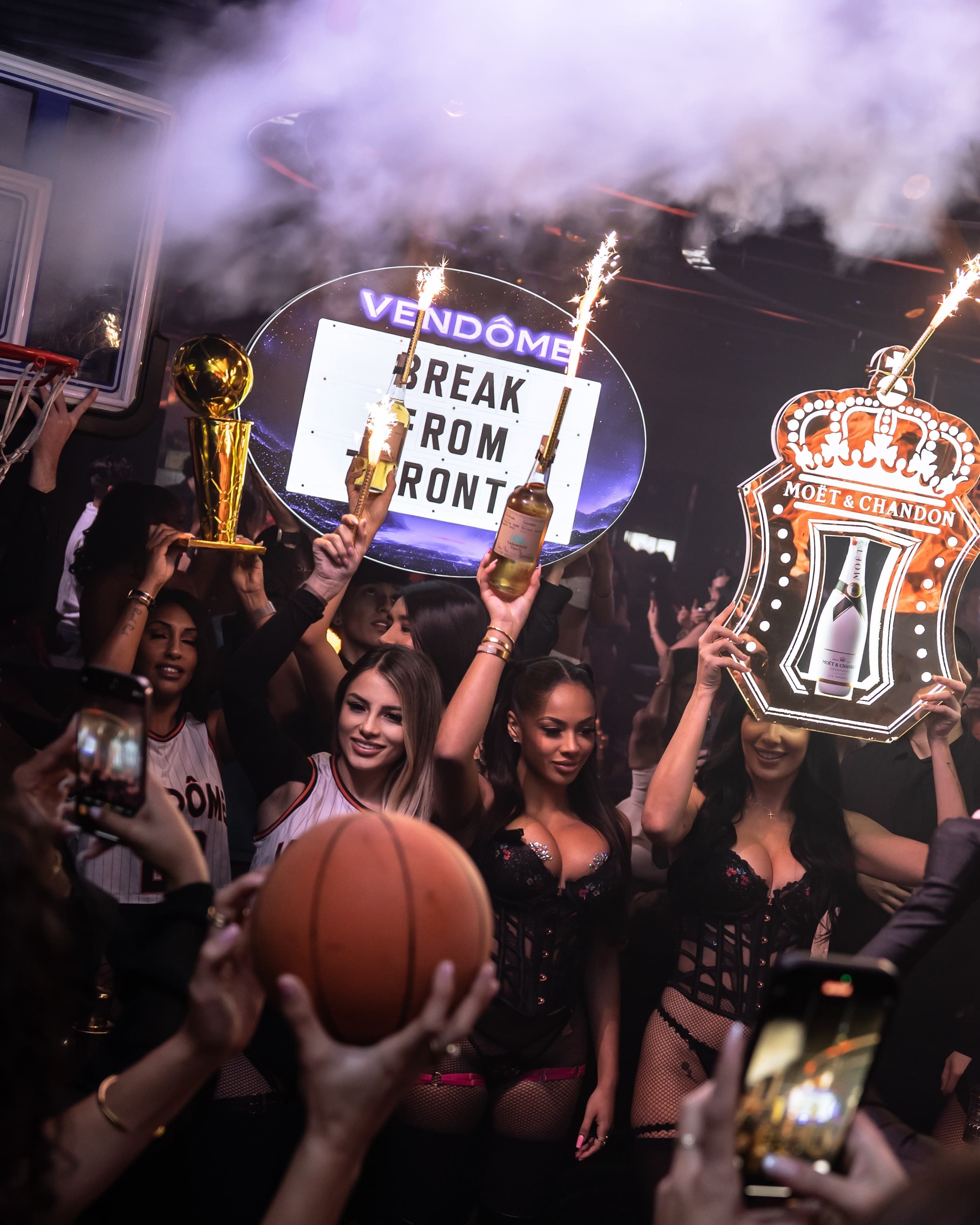 Vendôme staff carrying sparklers and an illuminated sign through the crowd on the main floor